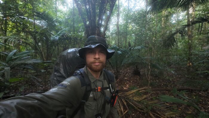 Swiss adventurer Loic Cappellin stands with his backpack surrounded by dense vegetation