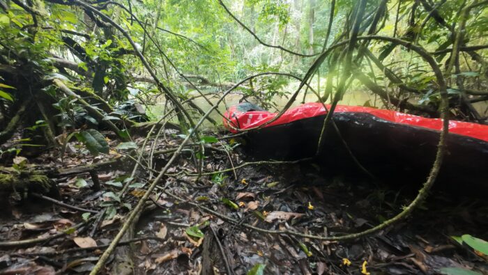 A red packraft deflated on the bank of a river