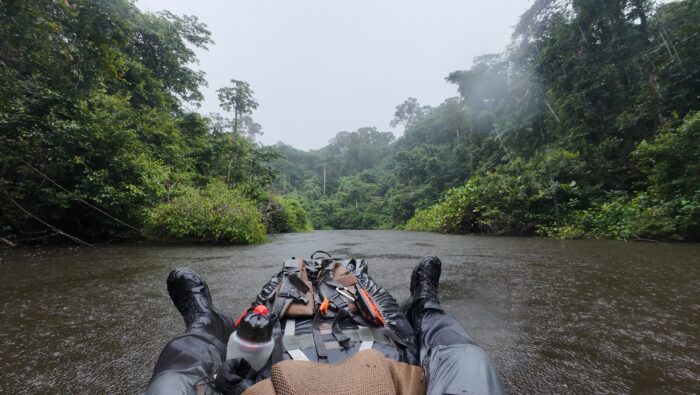 Legs of Swiss adventurer Loic Cappellin on a packraft as it floats down river