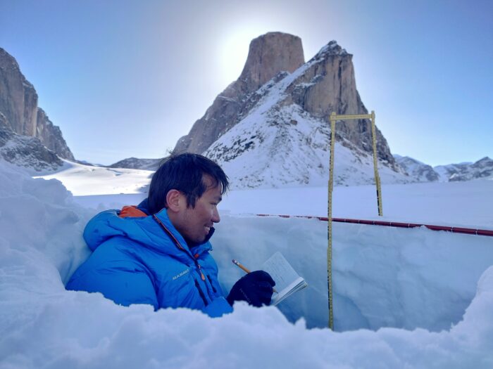 Wilson Cheung in a hole in the snow collecting snow data in an unnamed polar region