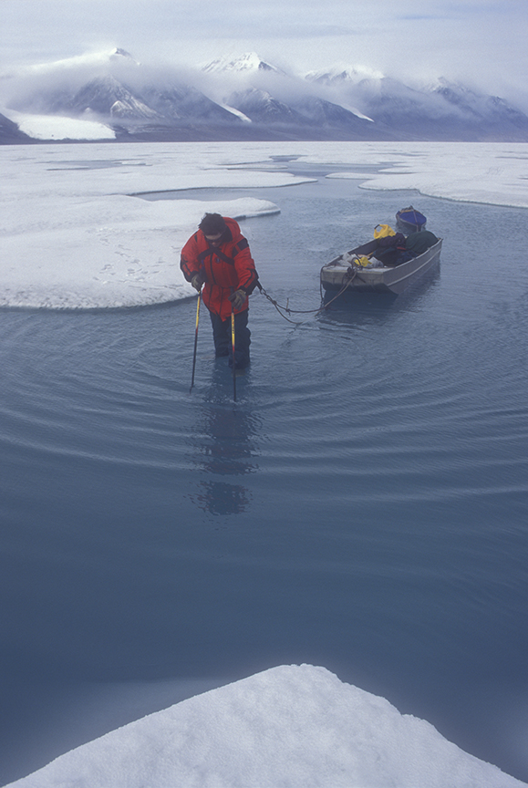 man hauling boat through water.