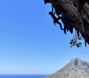 The shilouette of a climber with the Mediterranean sea and an island in background.