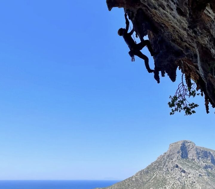 The shilouette of a climber with the Mediterranean sea and an island in background.