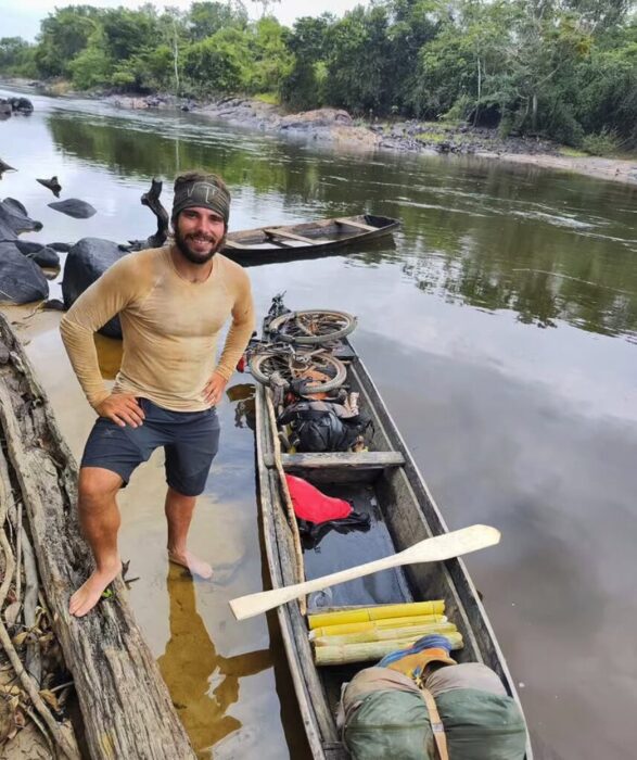 Italian adventurer Lorenzo Barone stands next to a wooden canoe in a jungle river in Brazil