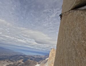 A climber on a difficult traverse at a vertical granite wall on Fitz Roy, Patagonia.