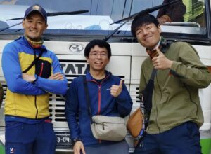 Three climbers in casual wear post in front of a truck.
