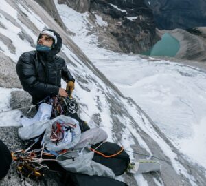A climber looks up from a half-destroyed portaledge on a Patagonian face.
