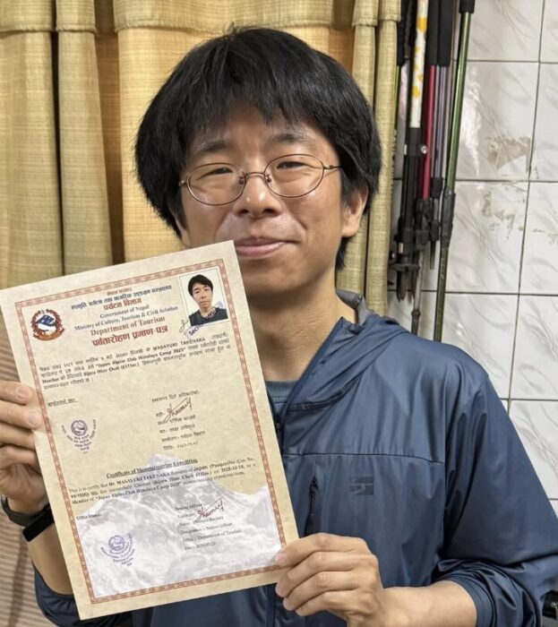 Japanese climber holding a climbng permit document.
