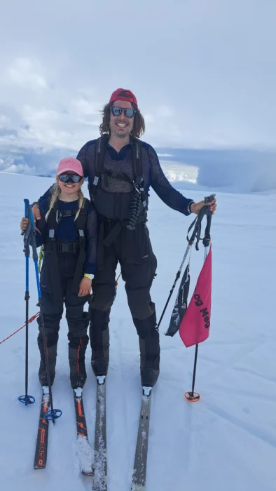 Norwegian daughter and father Mina and Alexander Read stand on skis in the snow.