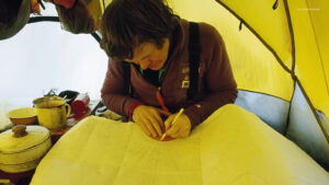 A man in a tent drawing a plan.