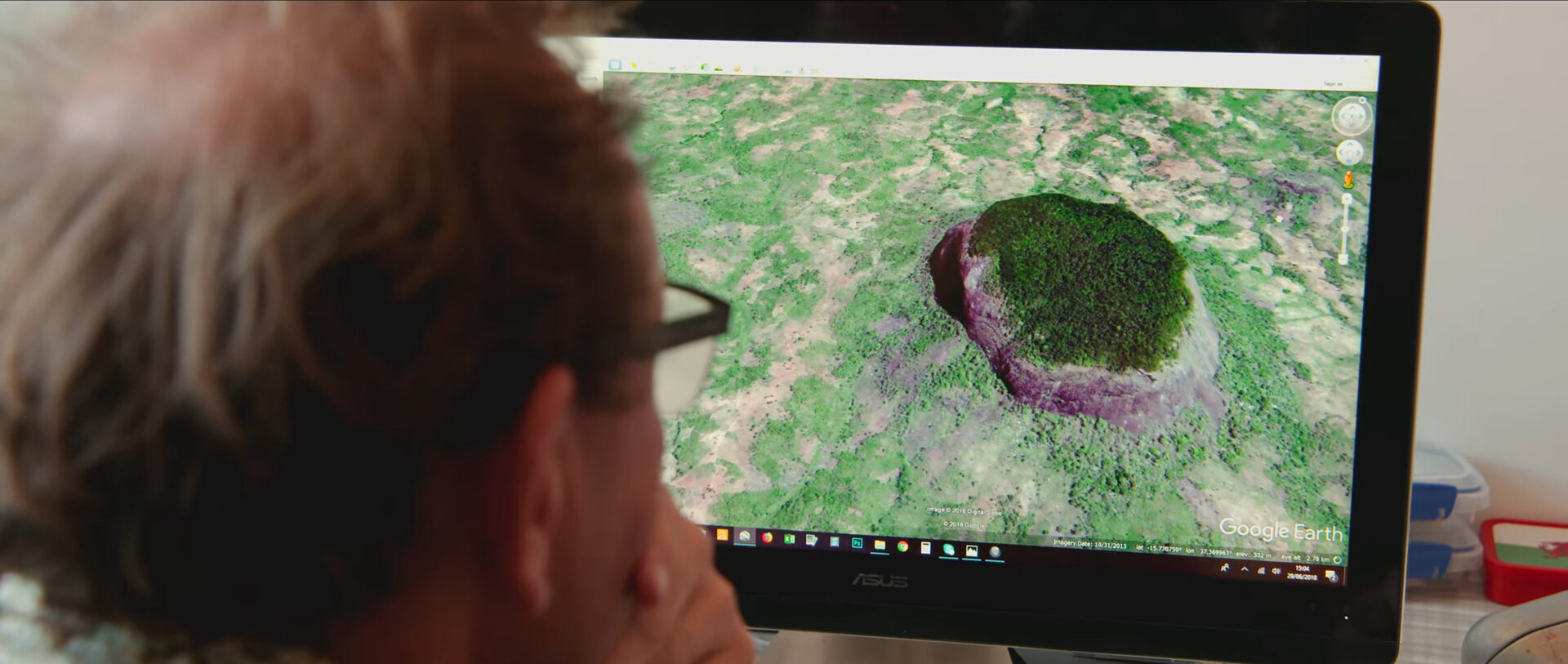 A man stares at satellite photos onscreen