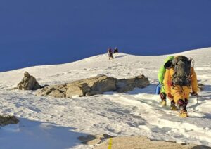 Climbers heading to a summit on a steep snow slope.
