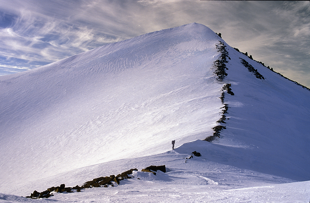 small figure climbing a snowy peak