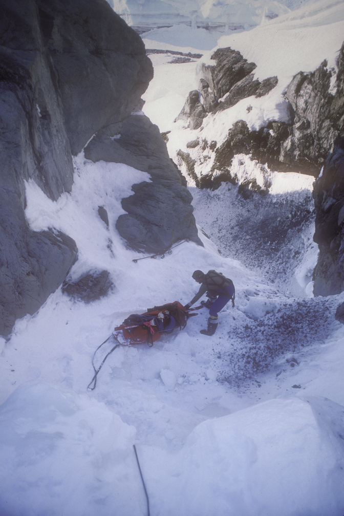 man lowering sled down cliff