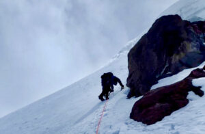 silhouetted climber on steep snow slope