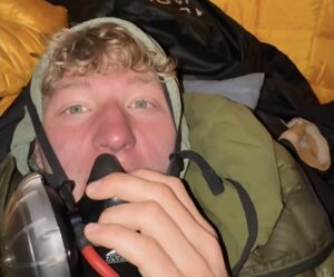 A climber speaking to the camera with an O2 mask on.