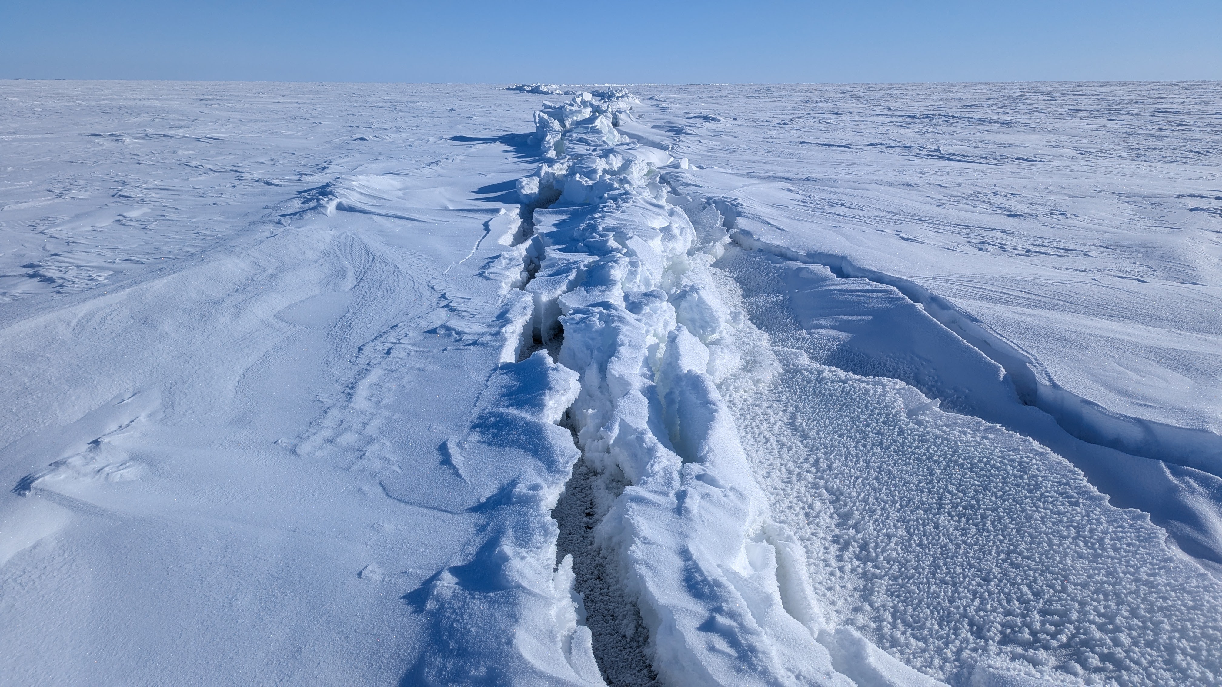 A crack in the ice runs vertically across a frozen Great Slave Lake