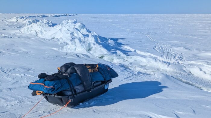 A sled sits next to a pressure ridge of ice breaking through a snow covered Great Slave Lake