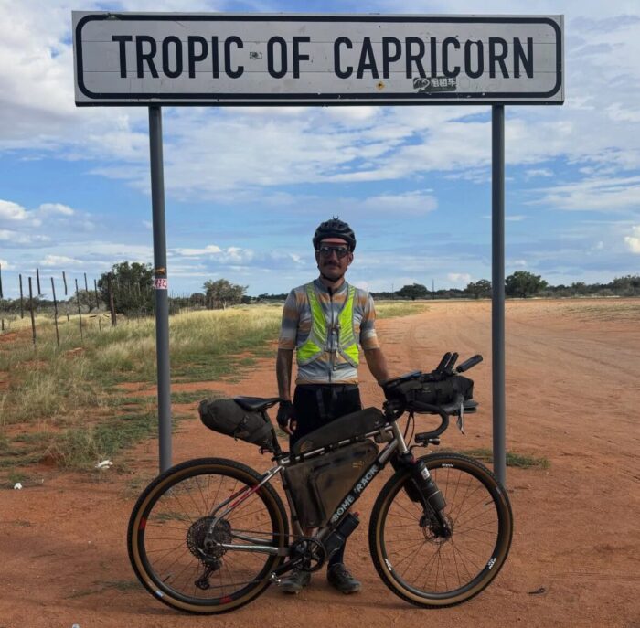 Swiss cyclist Adrien Liechti posting with his bike at the Tropic of Capricorn sign in Namibia