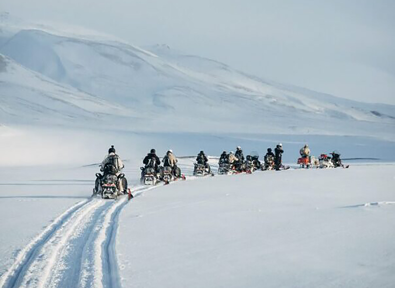 snowmobilers in an arctic landscape
