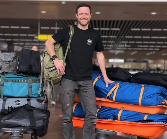 Gilles Denis standing with sleds and bags in an aiport