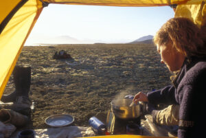 woman cooking in front of tent