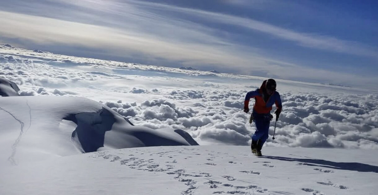Egloff running on the summit area of an Ecuador's nevado, with crampons, helmet and ice-axe in hand.