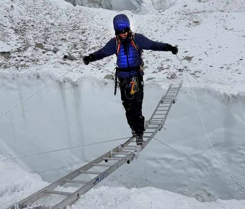 climber crossing ladders over a wide crevasse