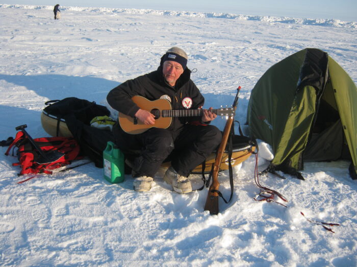 Czech polar guide Miroslav Jakes playing a guitar in the snow outside his tent
