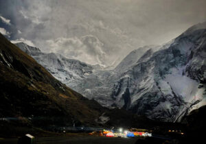 Annapurna base camp lit up in the night under a full moon.