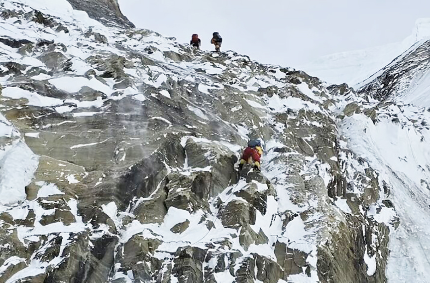 Climbers on an iced up rocky slope.