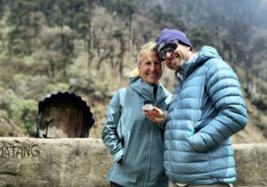 Two American climbers smile and pose with some jar of cream in an outdoor Nepal setting.