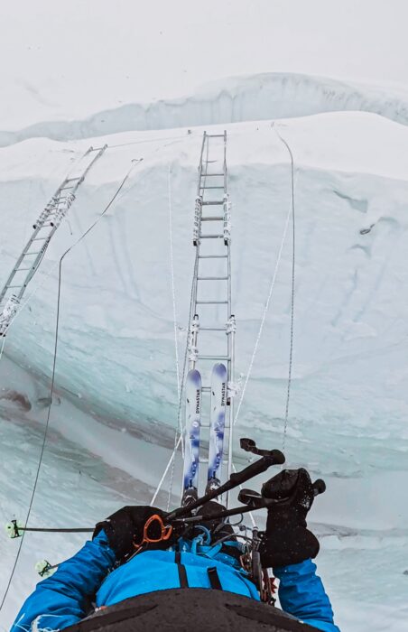 A pair of skis crossing a crevasse on an aluminium ladder. 