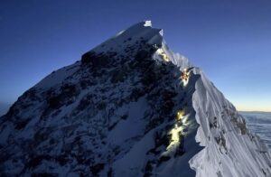Climbers with headlamps on at Everest's Hillary Step, with dawn barely clearing up the night sky.