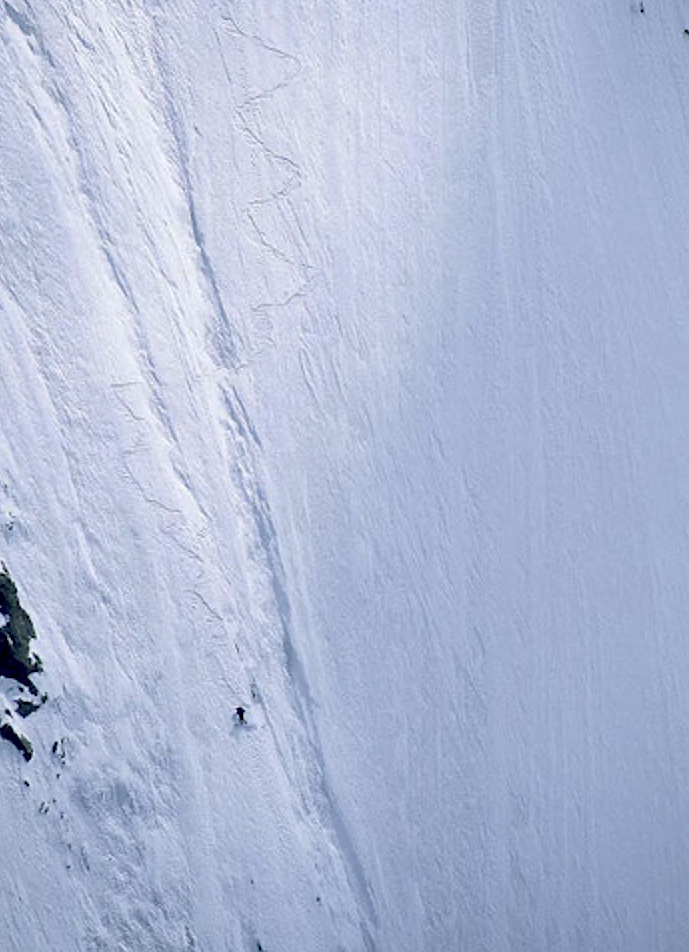tiny figure snowboarding down giant wall