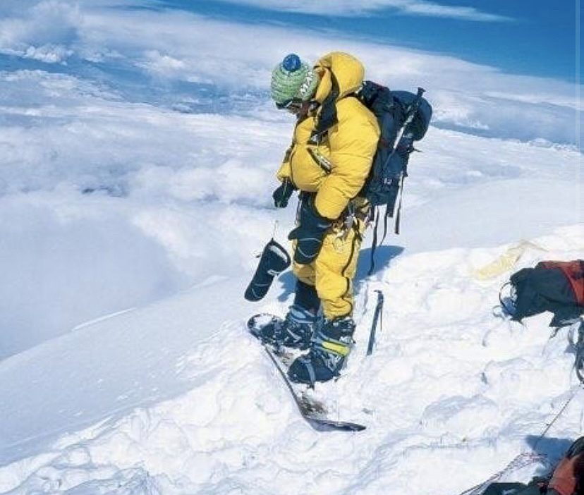 snowboarder in yellow atop giant mountain