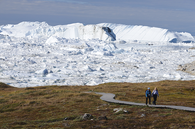 tourists on boardwalk beside icebergs