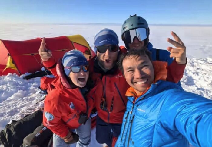 Four adventurers stand outside their tent on the Greenland Ice sheet