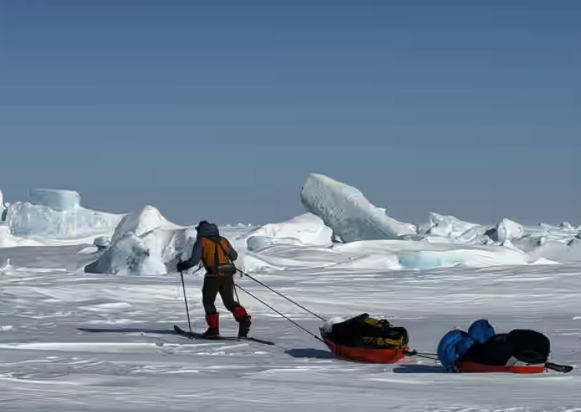 An adventurer skis past ice hummocks on sea ice near Mercy Bay, Nunavut
