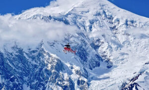 red helicopter in front of snowy giant montaon