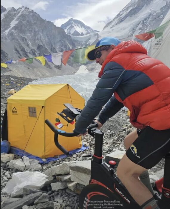 Tyler Andrews pedalling on a bycicle at Everest Base Camp. 