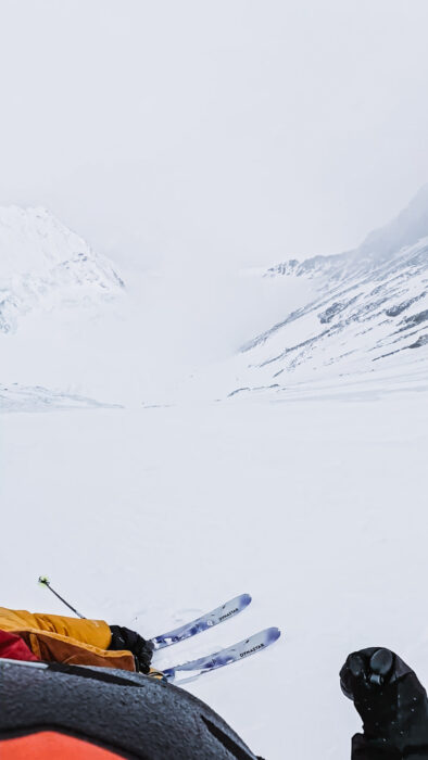 A pair of skis down a steep snow ramp on a foggy day. 