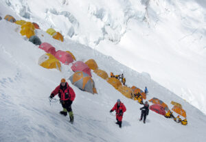 tents on the slope of Lhotse face and three climbers clipped to fixed ropes