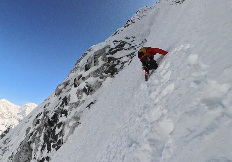 A climber on a vertical snow face. 