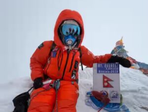 A climber with face mask and air-trimming mask on the summit of everest in a cloudy day.