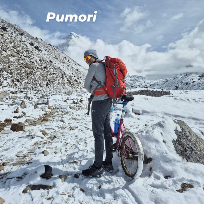 A guy dragging a bicycle on the snow-powdered morrain terrain near Everest Base Camp. 