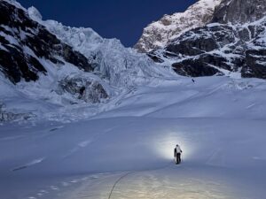 A lonely climber on a glacier, with an icefall marking a col between to mixed mountain faces.