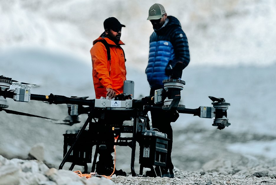 two guys stand beside large cargo drone
