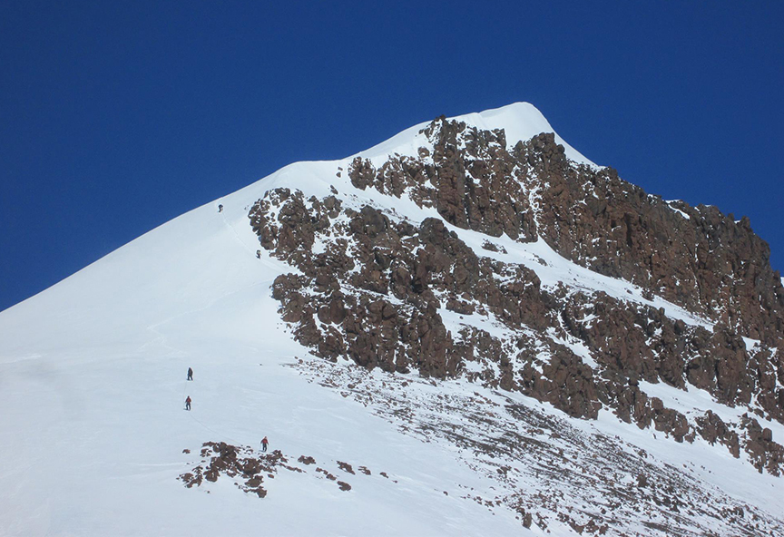 small figures go up a snowy slope