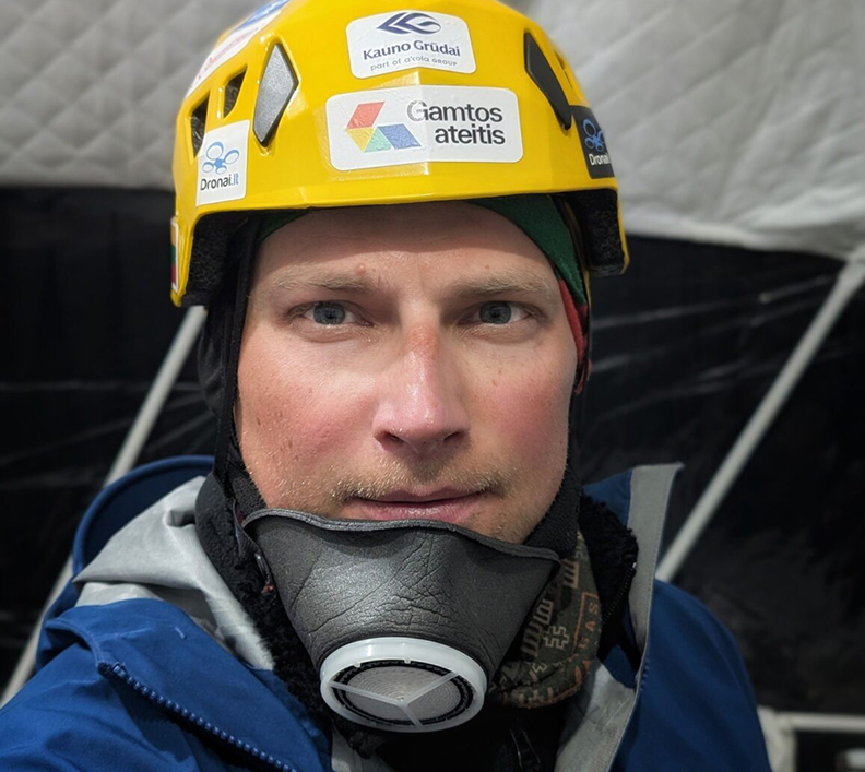 Close shot of Saulius Damulevicius with a helmet and an air-trimming mask down his chin.